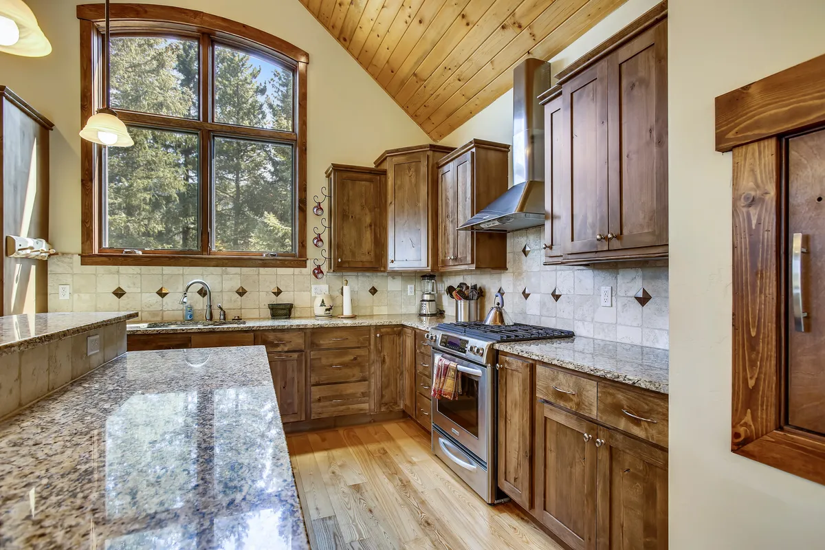 A beautifully appointed kitchen is the focus here, featuring a granite countertop, stainless steel appliances, a large window, and ample kitchen cabinetry. The scene feels both practical and inviting, perfect for cooking and entertaining.