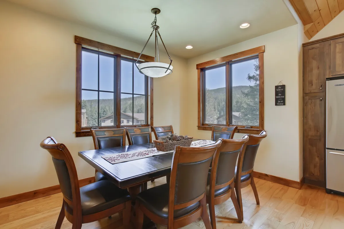 A bright interior dining space with a wooden table set near windows that frame scenic outdoor views. The warm lighting and inviting setting make it perfect for shared meals, casual conversations, and memorable celebrations with friends or family.