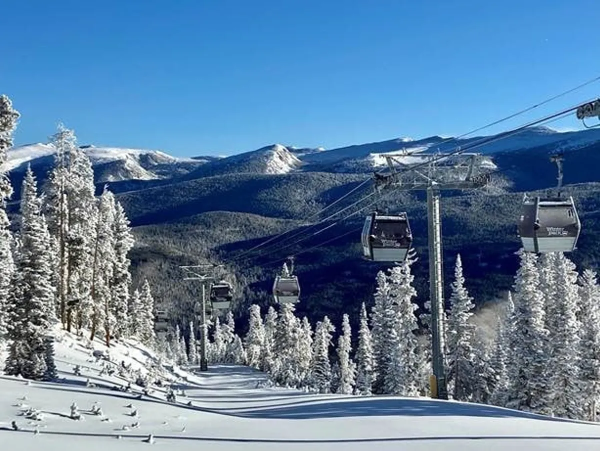 A breathtaking view of a ski lift gliding over snow-covered mountains and pine trees. The scene captures the essence of slope-side access, adventure, and the surrounding natural beauty of Winter Park Resort.