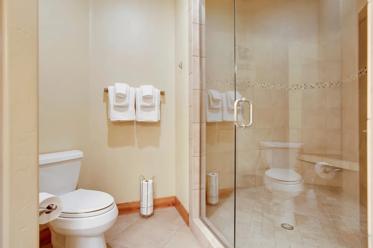A sparkling glass shower enclosure with white towels and a neutral color palette, creating a serene and luxurious space for rejuvenation.